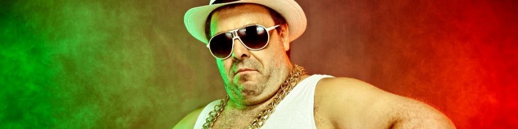 Un monsieur en marcel porte une grosse chaîne et un chapeau