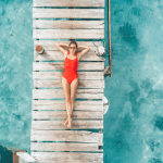 Une femme en maillot de bain rouge bonze sur un ponton vue du ciel