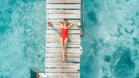 Une femme en maillot de bain rouge bonze sur un ponton vue du ciel