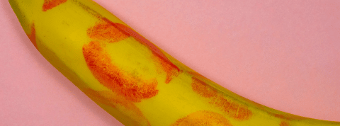 Post-vaccin, l'été sera chaud. Une banane recouverte de traces de rouge à lèvre sur fond rose