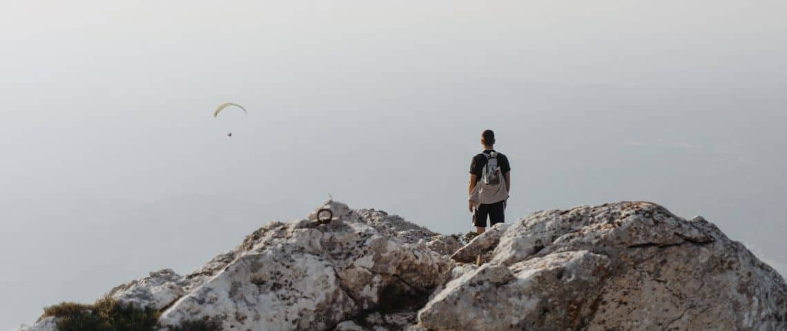 Un homme en haut d'une montagne. Il regarde au loin