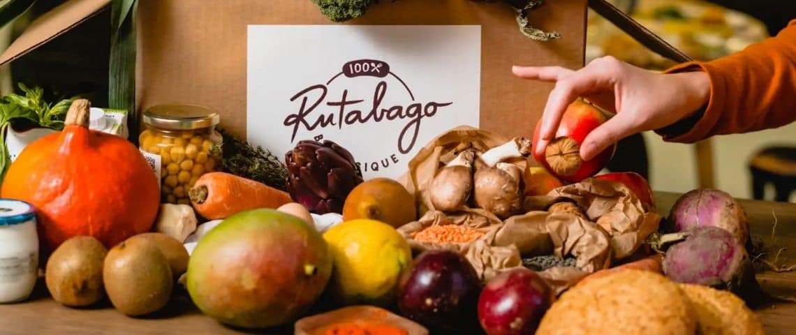 Rutabago-plats-express-livraison-france-start-up-alimentation-biologique-equilibree Des fuits et légumes. Une main saisit une noix. Un sac de la marque Rutabago en fond.