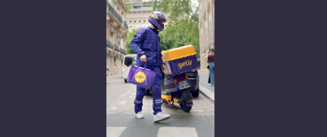 getir-livraison-rapide-produits-depicerie-paris-europe-service Un livreur à domicile à coté de son scooter