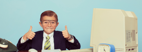 Economie, seconde main soldes...Les enfants s'intéressent aussi à l'argent. Un enfant en costume noir assis à un bureau le pouce en l'air