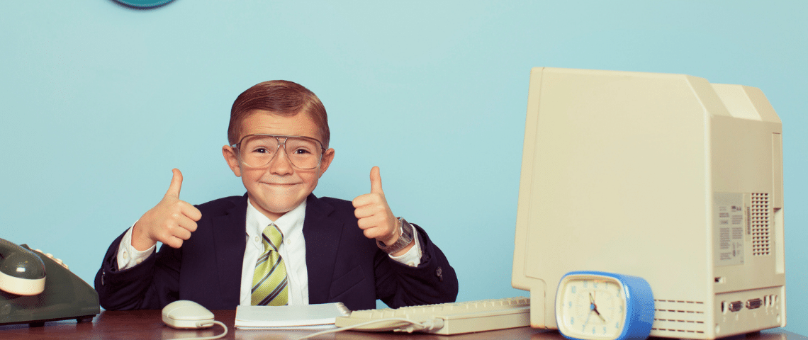 Economie, seconde main soldes...Les enfants s'intéressent aussi à l'argent. Un enfant en costume noir assis à un bureau le pouce en l'air