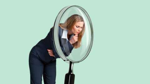 Une femme d'affaires regarde dans une loupe géante