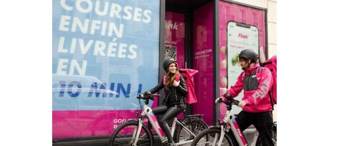 FLINK, la start-up de livraison rapide à domicile, lance une vaste campagne de recrutement national Deux personnes à vélo, avec une affiche : - Flink, courses enfin livrées en 10 minutes -
