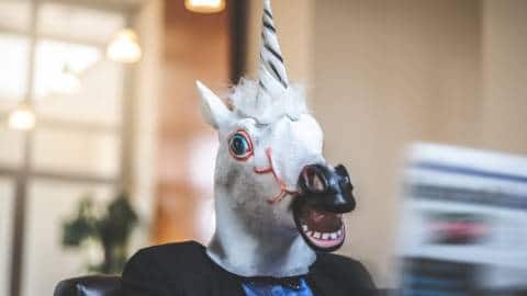 Un homme en masque licorne lit le journal