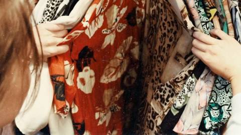 Une femme en train de regarder un portant de vêtements