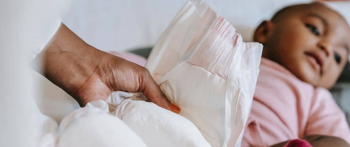 Fruit d’un partenariat entre Pampers, Carrefour et TerraCycle, ce pilote de collecte de couches bébé est une action concrète au service d’une consommation responsable Femme tenant une couche dans ses mains avec en arrière plan un bébé allongé