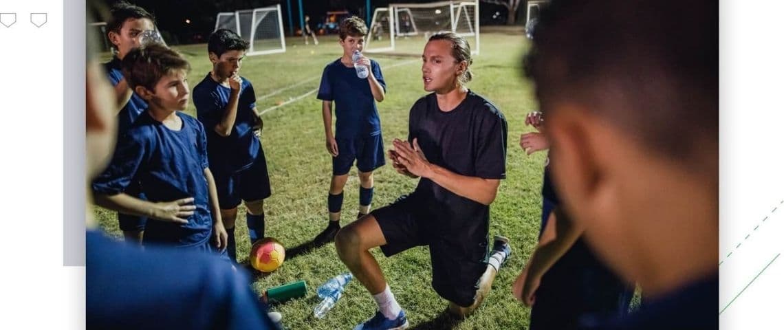 SportEasy lève 5 millions d’euros pour aider tous les clubs de sport amateur en Europe à se digitaliser Entraineur de sport agenouillé devant son équipe de jeuens garçons