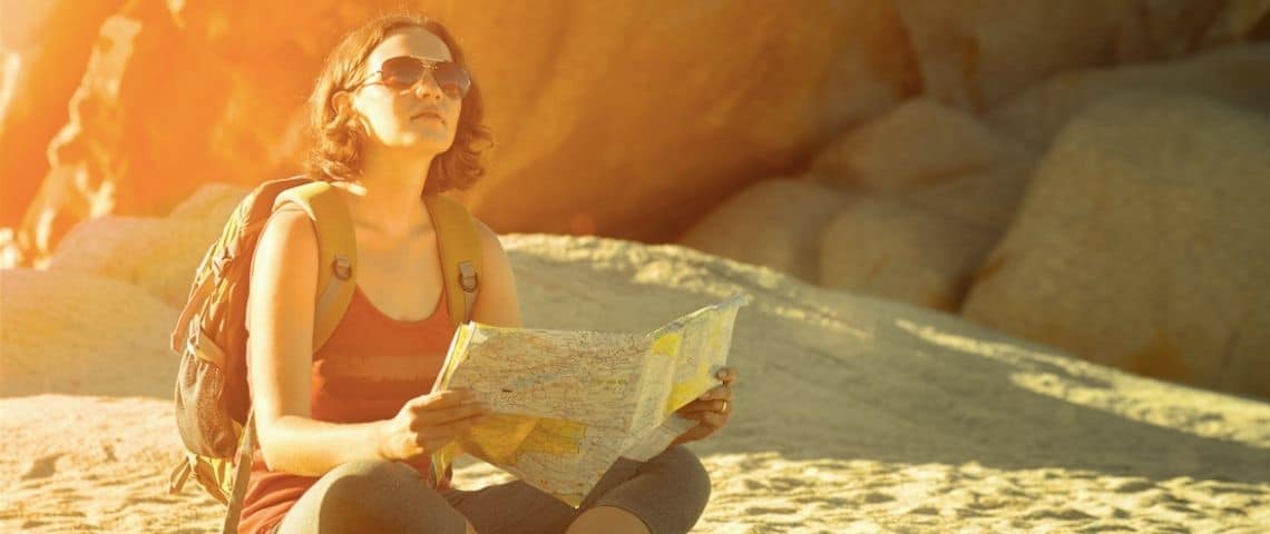 la-nouvelle-aquitaine-premiere-destination-securisee-pour-les-voyageuses-solos-la-voyageuse-application Une femme assise avec une carte et un sac à dos