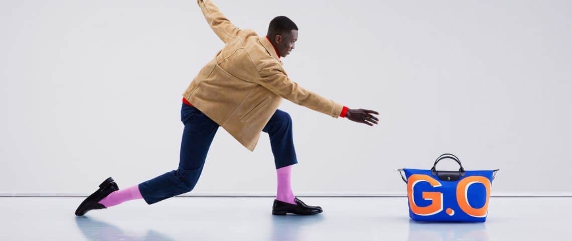 Longchamp dévoile avec Fred & Farid « It is not a bag. It is Le Pliage® » la 1ère campagne de marque pour sa ligne de sac emblématique lancée en 1993. Homme faisant glisser un sac - pliage - sur une piste de bowling