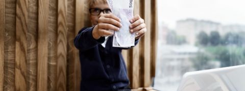 Mighty, l'appli qui transforme les enfants en mini Jeff Bezos Un petit garçon devant un ordinateur brandit une liasse de billets