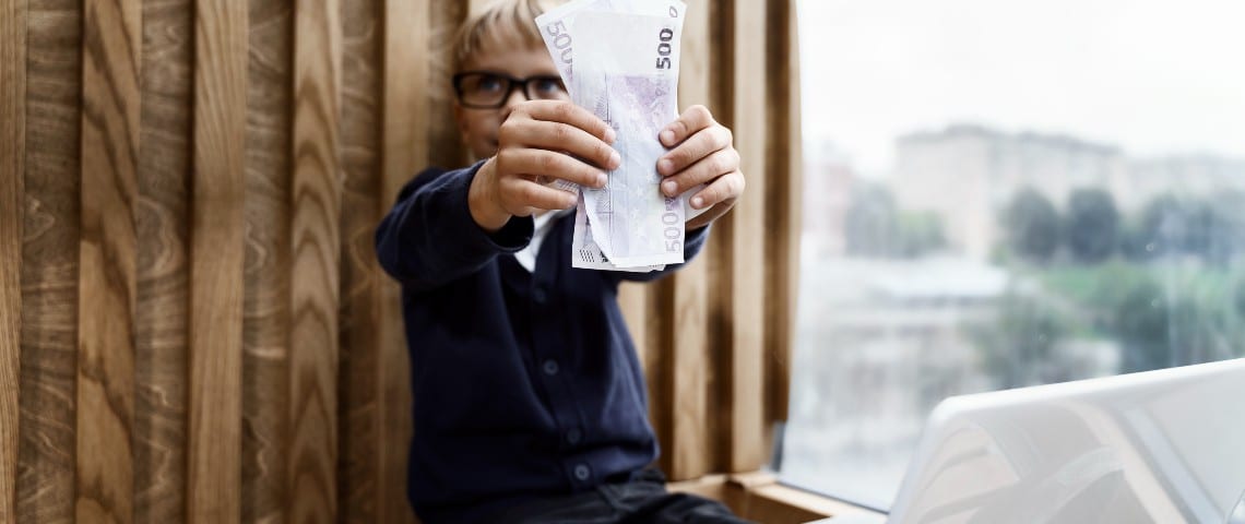 Mighty, l'appli qui transforme les enfants en mini Jeff Bezos Un petit garçon devant un ordinateur brandit une liasse de billets