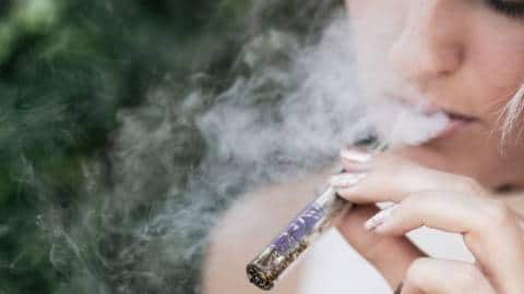 Une femme adulte en train de fumer une cigarette électronique