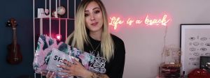 Une jeune fille blonde face tient un colis de la marque Shein
