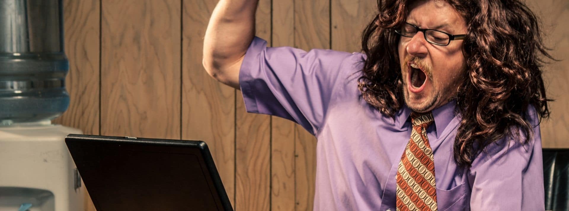 Finalement, pourquoi travailler? Un homme en chemise brandit le bras en criant face à son ordinateur