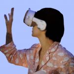 Jeune femme en pyjama rose sur fond bleu avec casque de réalité virtuelle sur la tête