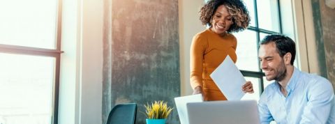 Booster de carrière, le mentorat a le vent en poupe ! Une personne explique quelque chose à une autre devant un ordinateur.