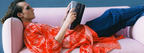 Homme aux cheveux longs lisant tranquillement dans son canapé