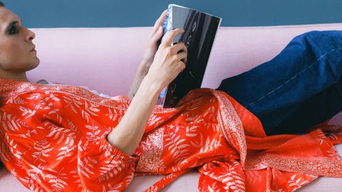 Homme aux cheveux longs lisant tranquillement dans son canapé