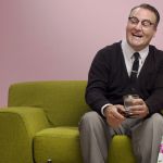 Couple années 50, riant en prenant l'apéro sur un canapé