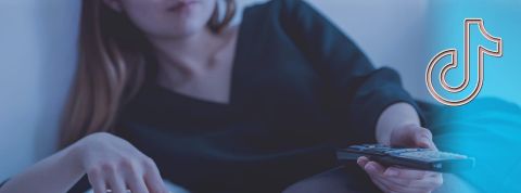 TikTok s'invite sur nos télés du salon Femme allongée avec télécommande dans la main et logo TikTok
