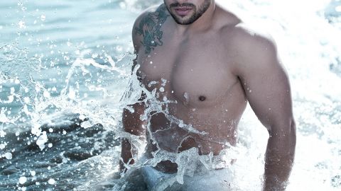 Homme sexy éclaboussé d'eau de mer