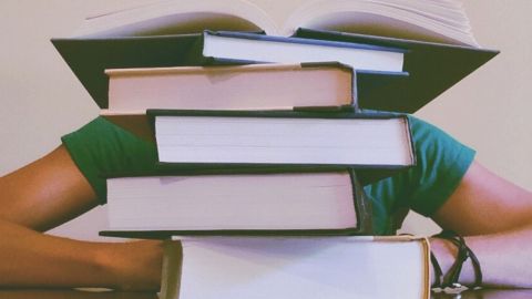 Un homme sous une pile de livre
