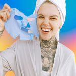 Jeune femme tatouée enlevant son masque beauté en souriant