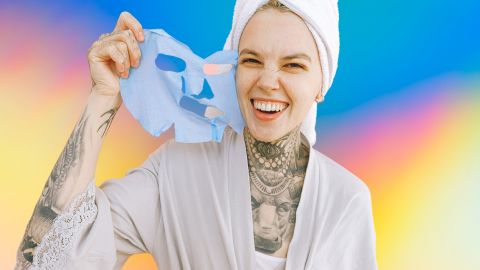 Jeune femme tatouée enlevant son masque beauté en souriant