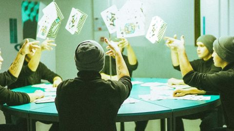Un groupe d'hommes identiques à une table de poker jettent leurs cartes en l'air