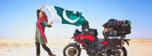 Rosie Gabrielle, influenceuse brandissant un drapeau pakistanais dans le désert, devant sa moto