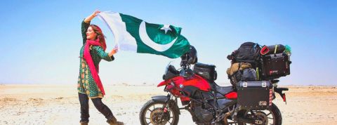 Rosie Gabrielle, influenceuse fan du Pakistan Rosie Gabrielle, influenceuse brandissant un drapeau pakistanais dans le désert, devant sa moto
