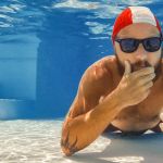 Homme au fond d'une piscine avec son portable
