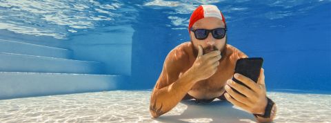 médias Homme au fond d'une piscine avec son portable