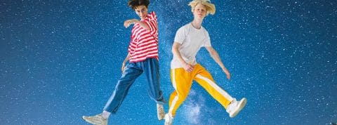 C'est quoi le quantum jumping ?  Deux jeunes hommes en tenues colorées devant un ciel étoilé