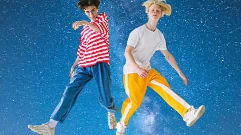 Deux jeunes hommes en tenues colorées devant un ciel étoilé