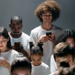 Sur fond gris, plein d'hommes et de femmes en train de regarder leur téléphone