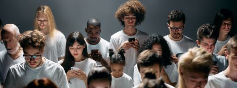 Tous accro à quelque chose ? Sur fond gris, plein d'hommes et de femmes en train de regarder leur téléphone
