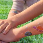 bras d'enfants avec tatouages planètes