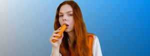 Jeune femme rousse croquant une carotte crue