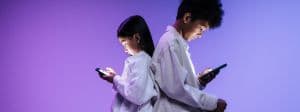 deux enfant de sexe opposé dos à dos en train de regarder leur smartphone
