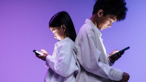 deux enfant de sexe opposé dos à dos en train de regarder leur smartphone