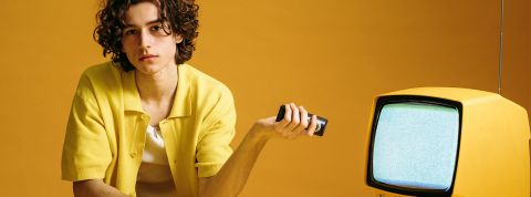Redevance audiovisuelle, la fin ? Jeune homme avec sa télécommande et TV, dans les tons jaunes