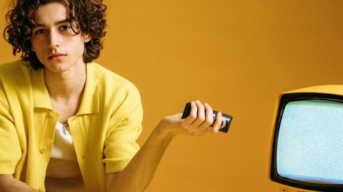 Jeune homme avec sa télécommande et TV, dans les tons jaunes