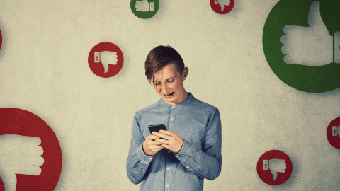 Un adolescent au milieu de pouces en l'air ou baissés