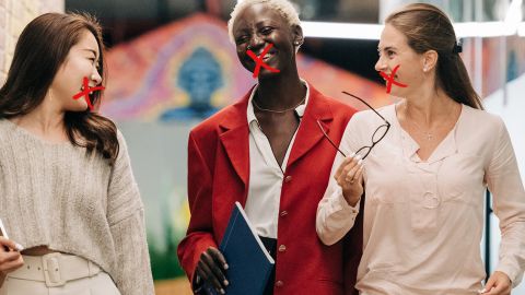 Trois salariées marchent dans un bureau, une croix rouge sur leur bouche