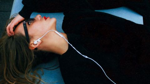 Une femme allongée porte des écouteurs